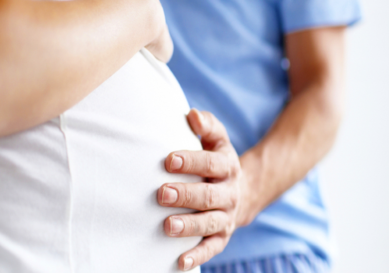 Una mano sosteniendo el vientre de una mujer embarazada